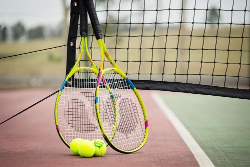 two tennis rackets and two tennis balls on a tennis court at Pokolbin Village Estate in Pokolbin