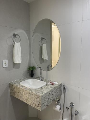 a bathroom with a sink and a mirror at Apides Palace Hotel Ltda in Pedro Canário