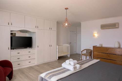 a bedroom with white cabinets and a flat screen tv at villa com piscina entre o mar e as montanhas in Paul do Mar