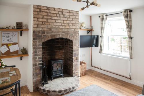 a living room with a brick fireplace at COSY COTTAGE ON BERNARDS HILL by SHIRE STAYS in Bridgnorth