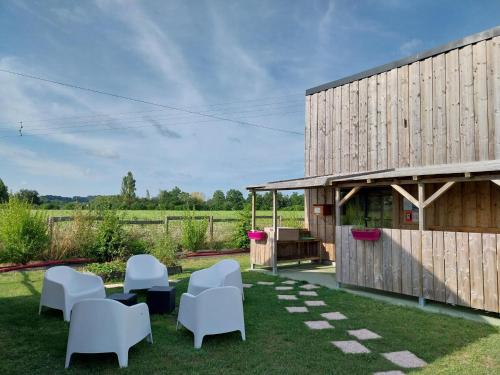 un jardin avec des chaises blanches et un bâtiment dans l'établissement CHALET CAMPAGNE - Climatisé - Les Belles Ouvrières, à Clermont-Créans