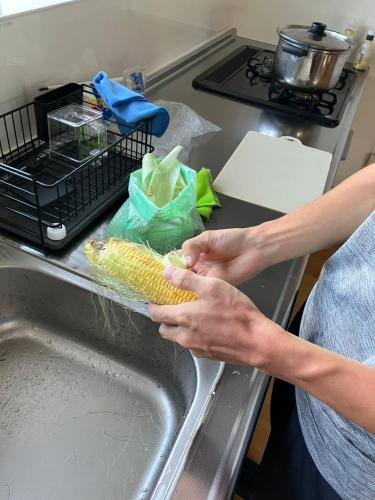 a person is washing corn in a sink at ゲストハウスわたうさぎ in Tsuruoka