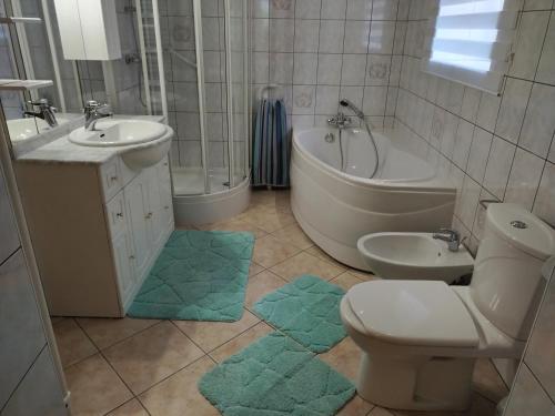a bathroom with a toilet and a tub and a sink at maison de vacances chez louis in Sondernach