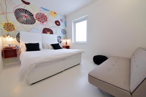 a white bedroom with a bed and a chair at Hotel Royal Paestum in Paestum