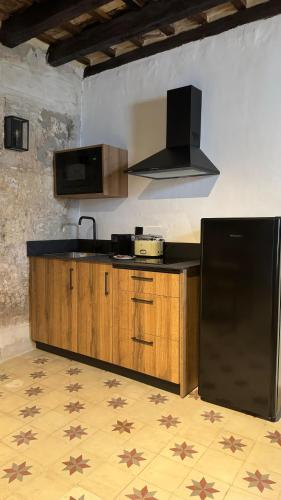 a kitchen with a black counter and a refrigerator at Apartamentos Jerez Siglo XIX in Jerez de la Frontera