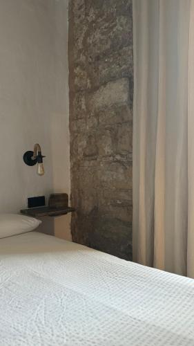 a bedroom with a stone wall and a bed with a curtain at Apartamentos Jerez Siglo XIX in Jerez de la Frontera