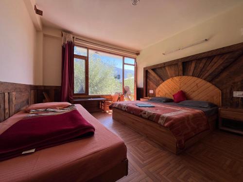 a bedroom with two beds and a large window at YOLO Social - The Social House & Cowork - Manali in Manāli