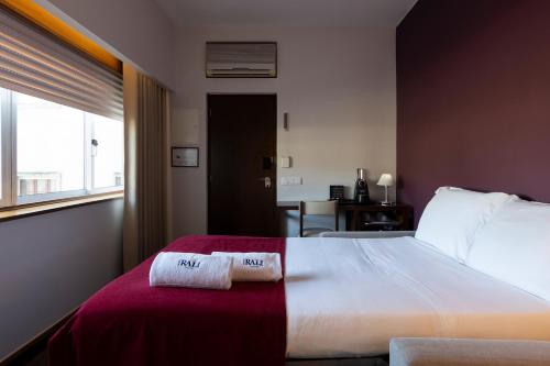 a bedroom with a large bed with two towels on it at Hotel Rali Viana in Viana do Castelo