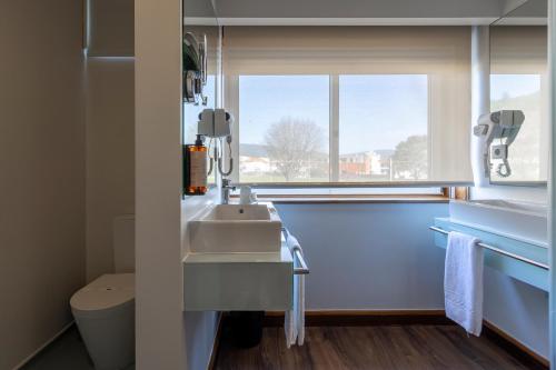 a bathroom with a sink and a window at Hotel Rali Viana in Viana do Castelo