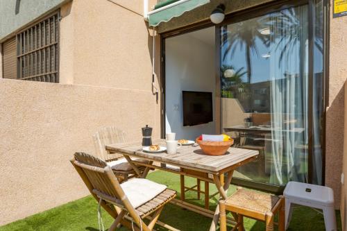 a wooden table and chairs on a patio with a television at BAJO primera línea playa, Retamar, Cabo de Gata in Retamar