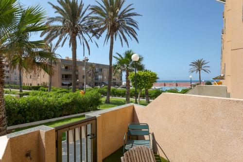 two chairs sitting on a balcony with palm trees at BAJO primera línea playa, Retamar, Cabo de Gata in Retamar