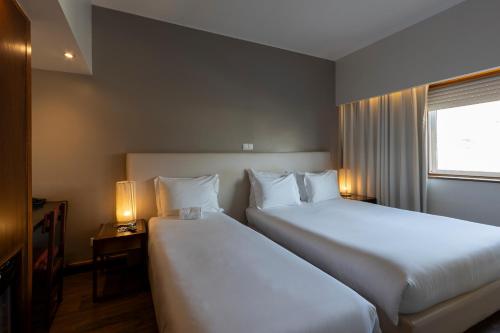 a hotel room with two beds and two lamps at Hotel Rali Viana in Viana do Castelo