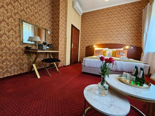 a hotel room with a bed and a table with flowers on it at Hotel Galicja SPA Wieliczka in Wieliczka