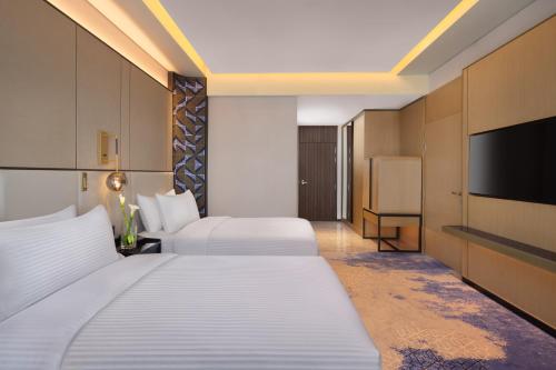 a hotel room with two beds and a flat screen tv at Amari Colombo, Sri Lanka in Colombo