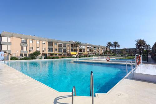 a large swimming pool with palm trees and buildings at BAJO primera línea playa, Retamar, Cabo de Gata in Retamar