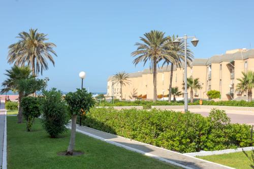 a park with palm trees in front of a building at BAJO primera línea playa, Retamar, Cabo de Gata in Retamar