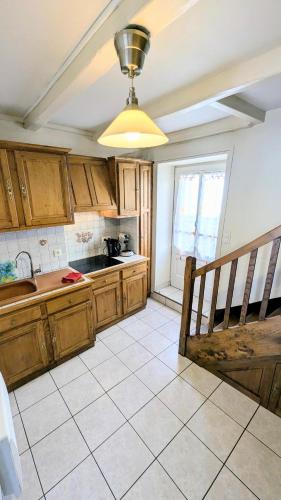 une cuisine avec des armoires en bois et un sol carrelé dans l'établissement Maison de village classé petite cité de caractère, à Foussais