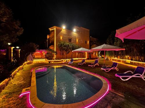 a swimming pool at night with chairs and umbrellas at فيلا إيجار في التجمع الخامس Vip Luxury home in Cairo