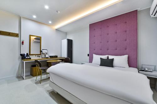 a bedroom with a large bed with a pink headboard at sweet hotel in Gimcheon
