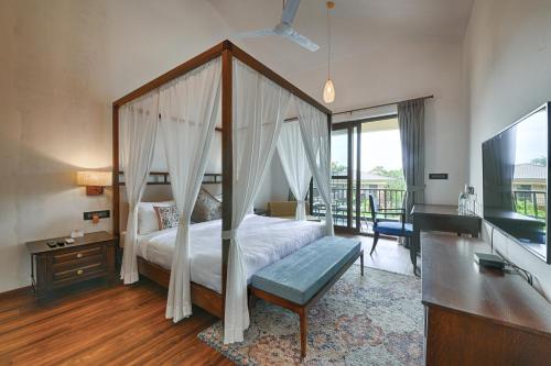 sypialnia z łóżkiem z baldachimem i telewizorem w obiekcie Melhor Stays Villa - L-A2 Luxury 3BHK villa with Private pool, Assagao w mieście Vagator