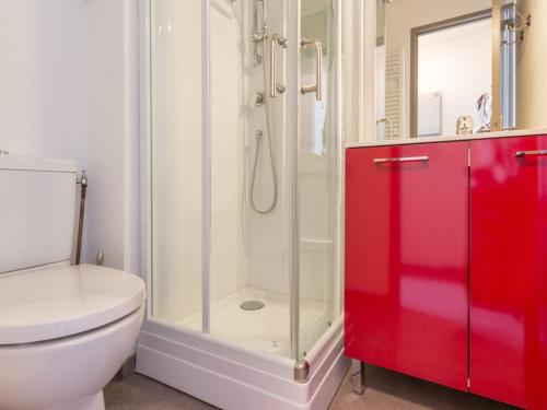 La salle de bains est pourvue de toilettes, d'une douche et d'une armoire rouge. dans l'établissement Studio rénové au pied des pistes - FR-1-181-2472, à Aime La Plagne