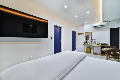 a bedroom with a large white bed with a flat screen tv at sweet hotel in Gimcheon