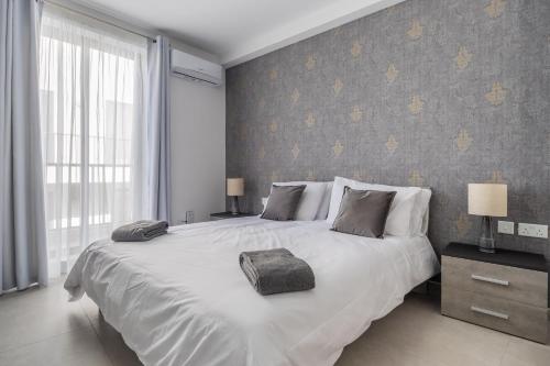 una camera da letto con un grande letto bianco e una finestra di Chic Downtown Hideaway a Msida