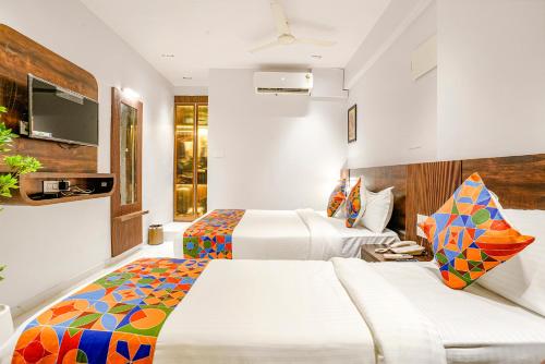 a hotel room with two beds and a tv at FabHotel Peralz - Nr Boriwali Station in Mumbai