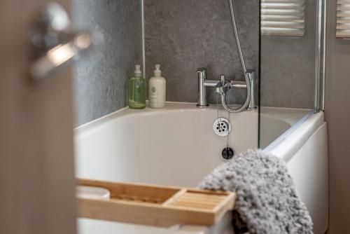 a bathroom with a bath tub with a shower at Lodge No 83 - Stewart's Resort Cameron in St. Andrews