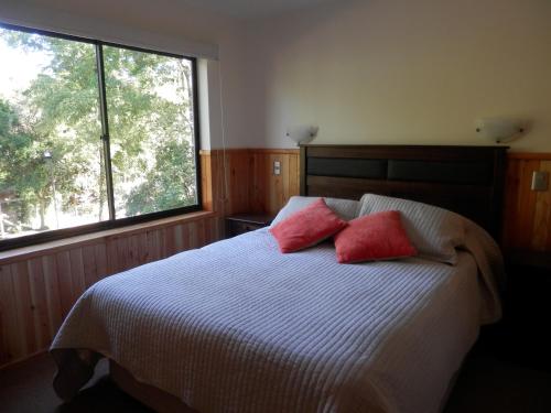 um quarto com uma cama com duas almofadas vermelhas em Parque Suizo Pucón Apartment em Pucón