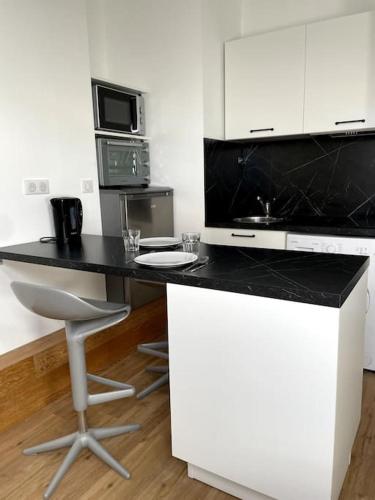 une cuisine avec un comptoir noir et une chaise dans l'établissement Clim-Ascenseur T2 Capitole à 5' Gare à 7', à Toulouse