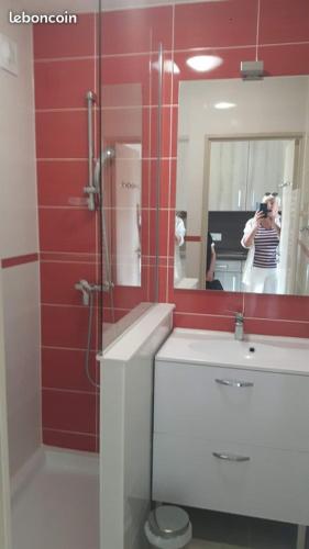 une femme prenant une photo d'une salle de bains avec miroir dans l'établissement La Corniche d'Or à St Raphael, à Saint-Raphaël