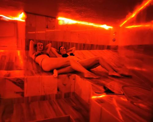 two women laying on a bed in a room with red lights at Beach house BellaVista with hot pool in Trogir