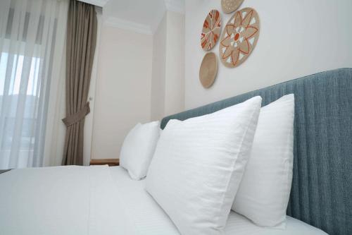 a bedroom with a white bed with white pillows at Port Selene Otel in Kışlabucağı