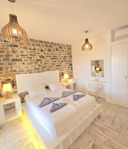 a bedroom with a large white bed and a brick wall at Paros Afrodite Luxury Villas in Aliki
