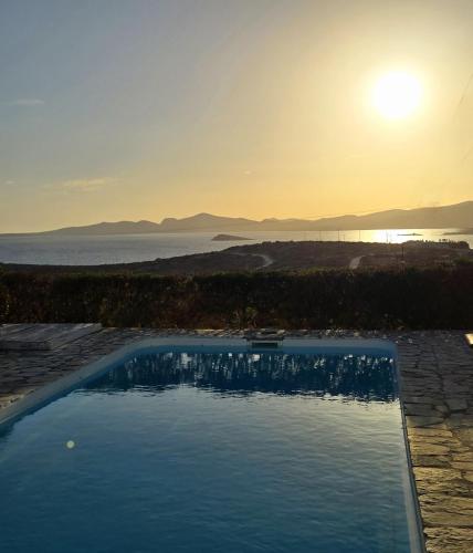 a swimming pool with the sunset in the background at Paros Afrodite Luxury Villas in Aliki