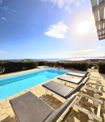 a pool with chaise lounge chairs and a swimming pool at Paros Afrodite Luxury Villas in Aliki