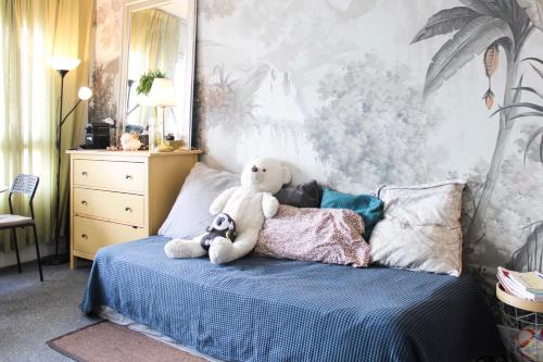 un ours en peluche assis sur un lit dans l'établissement Bright studio in the heart of Paris, à Paris