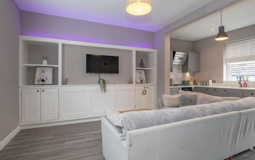 a living room with a white couch and a tv at Number 3 Castle Cottage in Skipton
