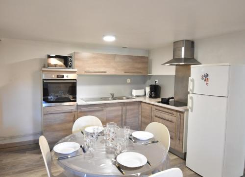 Il comprend une cuisine équipée d'une table avec des chaises et d'un réfrigérateur blanc. dans l'établissement Aire Ona 2 - Hossegor appartement situé à proximité de la plage de la gravière, à Soorts-Hossegor