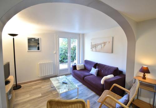 un salon avec un canapé violet et une table dans l'établissement Aire Ona 2 - Hossegor appartement situé à proximité de la plage de la gravière, à Soorts-Hossegor