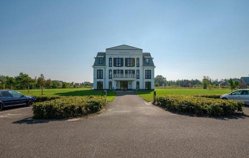 a large white house with cars parked in a parking lot at 2 Bedroom Nice Apartment In Kamperland in Kamperland