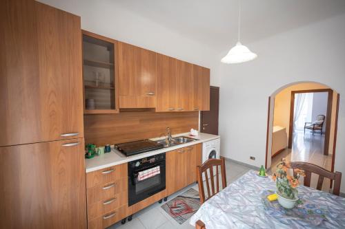 a kitchen with wooden cabinets and a table with a dining room at Casa bea in Taranto