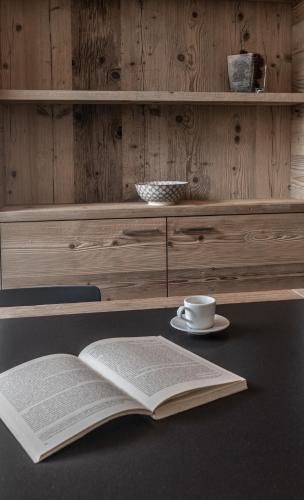 an open book sitting on a table with a cup and a coffeeucer at BAITA LARIX BORMIO in Bormio