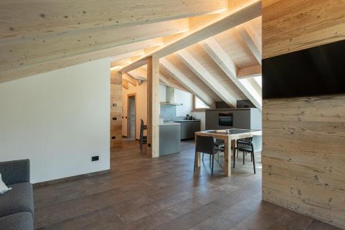a kitchen and dining room with wooden ceilings and a table at BAITA LARIX BORMIO in Bormio