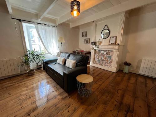 a living room with a black couch and a table at Duplex au lin in Saint-Pol-de-Léon