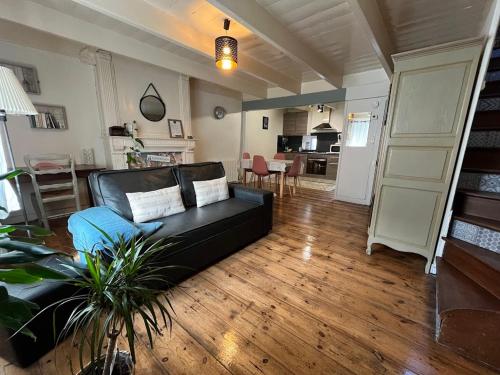 a living room with a black couch and a kitchen at Duplex au lin in Saint-Pol-de-Léon