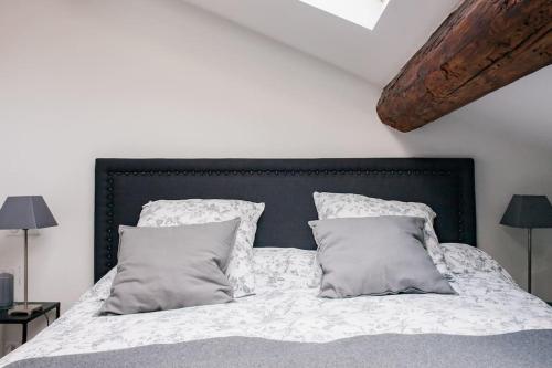 une chambre avec un lit avec des draps blancs et des oreillers dans l'établissement Baignez dans la lumière d'un loft nîmois au caractère unique, à Nîmes