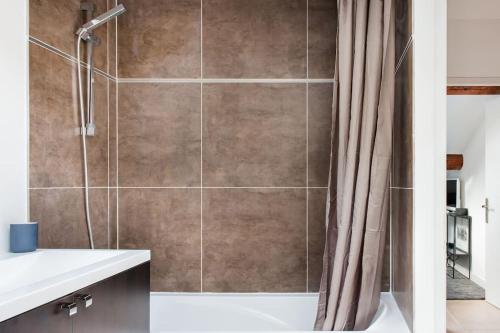 une salle de bain avec une douche avec un rideau de douche dans l'établissement Baignez dans la lumière d'un loft nîmois au caractère unique, à Nîmes