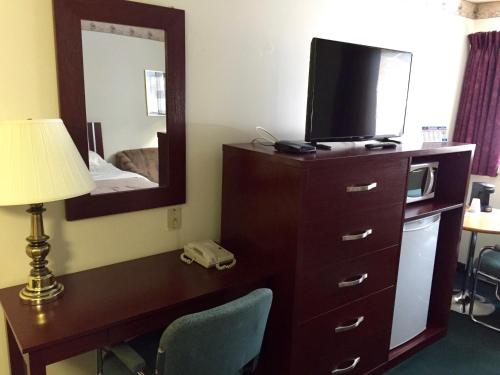 a hotel room with a dresser with a television on it at Colonial Inn in Brandon